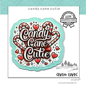 May include: A white card with a teal border featuring the words "Candy Cane Cutie" in a decorative font, candy canes, and hearts. The design includes a red bow and stars. A small illustration of trees is at the bottom.