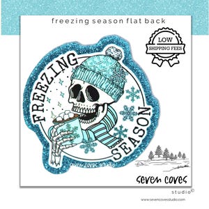 May include: A teal glitter flat back with a skull wearing a teal knit cap and scarf, holding a mug of hot cocoa. The words "FREEZING SEASON" are in a circle around the skull. The image also includes snowflakes and the text "seven coves studio".