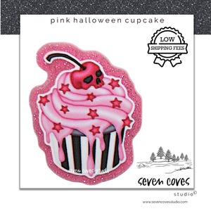May include: A pink Halloween cupcake design with a cherry skull on top and star accents. The cupcake has pink frosting with red star sprinkles and black and white striped base. The text "pink halloween cupcake" is at the top.