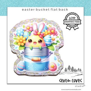 May include: A flat back Easter bucket with a cute bunny and pastel colored eggs. The bucket is decorated with glitter and flowers. The text "Seven Coves Studio" is at the bottom of the image.