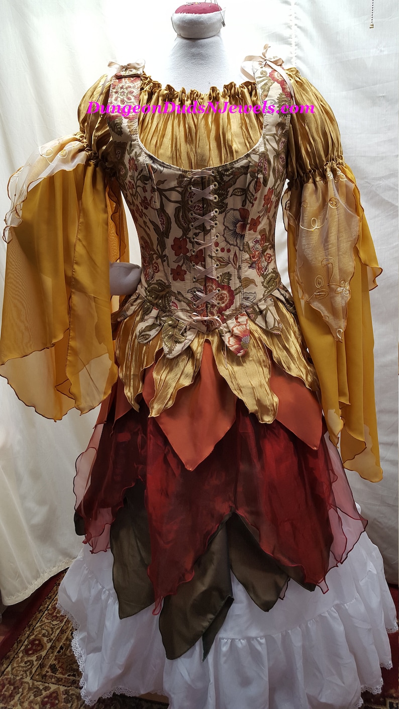 K&ouml;nnte beinhalten: Ein mehrlagiges, herbstliches Kleid mit einem floralen Oberteil, einem gold- und braunen, gerafften Rock und durchsichtigen gelben &Auml;rmeln. Das Kleid hat einen wei&szlig;en Unterrock.