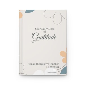 Op de afbeelding: Een beige notitieboek met een bloemenontwerp en de tekst "Your Daily Dose of Gratitude" en "In all things give thanks" 1 Thes 5:18.