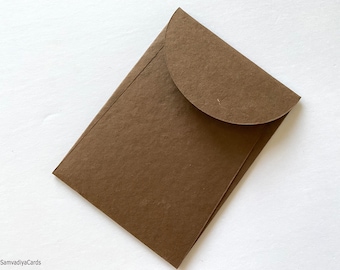 May include: A brown paper envelope with a rounded flap. The envelope is made of a textured paper.