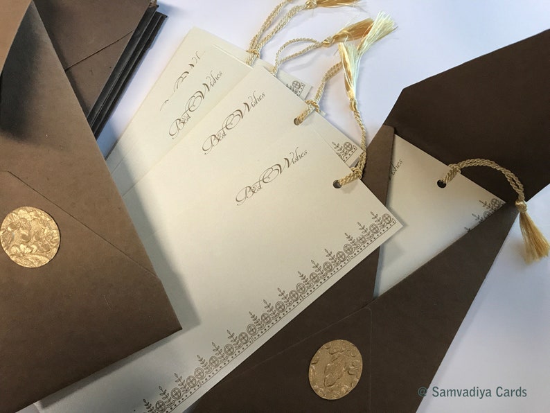 May include: A set of ivory-coloured cards with gold trim and the words "Best Wishes" printed on them. The cards are packaged in brown envelopes with gold seals.