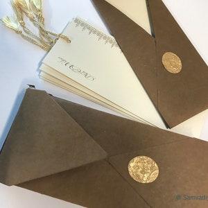 May include: A set of brown envelopes with gold wax seals. The envelopes are folded and ready to be mailed. The envelopes are decorated with a gold tassel.