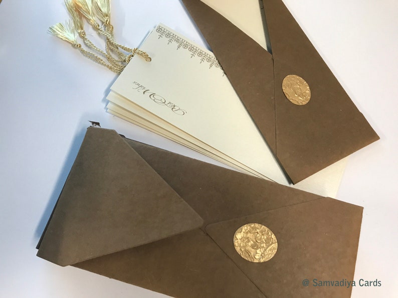 May include: A set of brown envelopes with gold wax seals. The envelopes are folded and ready to be mailed. The envelopes are decorated with a gold tassel.