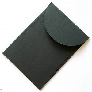 May include: A black envelope with a rounded flap. The envelope is made of a thick, textured paper.