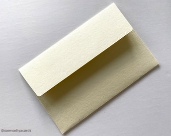 May include: A cream-colored envelope with a flap. The envelope is made of a textured paper.