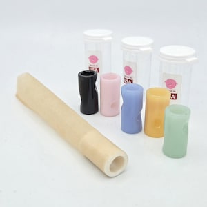May include: A long, cylindrical, beige tube alongside five small, colorful, cylindrical components in black, pink, blue, yellow, and light green. Three clear plastic containers with white lids and labels featuring a pink pig icon and the text MADE IN USA.