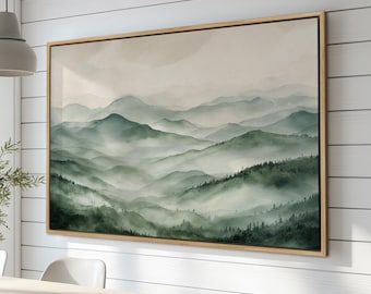 Puede incluir: Una impresión sobre lienzo enmarcada de una pintura de acuarela que representa un paisaje montañoso brumoso con colinas onduladas y árboles verdes exuberantes.