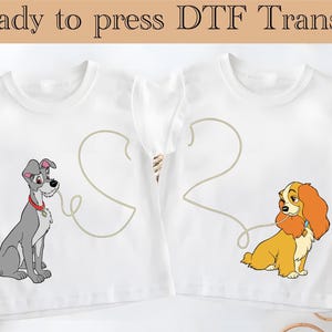 May include: Two white t-shirts with a graphic design of a cartoon dog and a cartoon dog with a heart-shaped string connecting them. The text "Ready to press DTF Transfer" is at the top of the image.