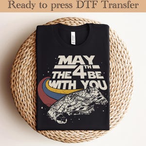 May include: Black t-shirt with a vintage-style graphic of a spaceship and the text "May the 4th be with you".