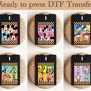 May include: Black t-shirts with colorful cartoon character designs. Each shirt features a grid of four character faces, including Mickey Mouse, Minnie Mouse, Donald Duck, Goofy, Pluto, and Daisy Duck. The text "Ready to press DTF Transfer" is at the top.
