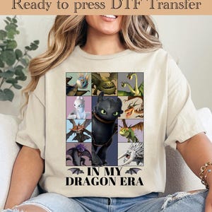 May include: Beige t-shirt featuring a grid of colorful dragon illustrations. The shirt has the text "IN MY DRAGON ERA" in black font. The words "Ready to press DTF Transfer" are at the top.