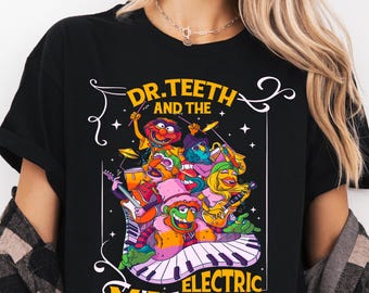 Pode incluir: Camiseta preta com um gráfico colorido de Dr. Teeth e da banda Electric Mayhem. O design inclui vários personagens dos Muppets tocando instrumentos em um teclado de piano. O texto na parte superior diz "Ready to press DTF Transfer".