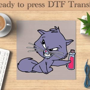 Puede incluir: Imagen de dibujos animados de un gato morado con expresión enfadada, sosteniendo una botella de líquido rojo. El texto "Ready to press DTF Transfer" está en la parte superior. La imagen está sobre una superficie de madera, con una taza de café, teclado y planta.