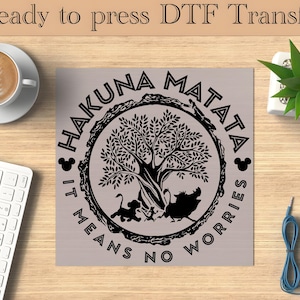 Może przedstawiać: Czarno-biały projekt graficzny przedstawiający drzewo z napisem "Hakuna Matata It Means No Worries" wokół niego.