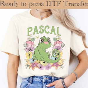 Könnte beinhalten: Ein weißes T-Shirt mit einem grünen Chamäleon mit einem Blumendesign und dem Wort "PASCAL" darauf gedruckt.
