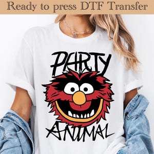 May include: White t-shirt with a cartoon graphic of a red, black, and yellow character and the words "PARTY ANIMAL" in black. The text "Ready to press DTF Transfer" is printed at the top of the image.