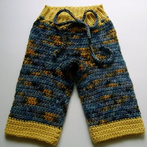 Puede incluir: Pantalones de bebé tejidos a crochet en azul y amarillo con un lazo en la cintura.