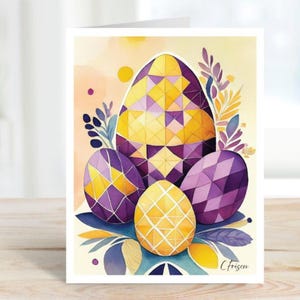 May include: Easter greeting card featuring watercolor illustrations of four decorated eggs in shades of yellow and purple. The eggs are surrounded by stylized leaves and floral elements. The card is on a white background.
