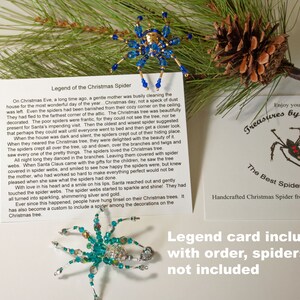 May include: A card featuring a blue and gold beaded spider ornament and a red beaded spider ornament. The card includes the text "Legend of the Christmas Spider" and "Enjoy your Treasures by Tiziana The Best Spiders on the WEB TM Handcrafted Christmas Spider from the Artist Tiziana". The card also has the text "Legend card included with order, spiders are not included".