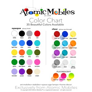 May include: Color chart for Atomic Mobiles, a company that makes mobiles. The chart shows 35 different colors in two categories: opaque and clear. The opaque colors are shown in solid circles, while the clear colors are shown in translucent circles. The chart also includes a section for fluorescent colors.