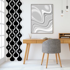 May include: A mid-century modern interior with a wooden desk, gray chair, and abstract art. Black and white patterned curtains hang near a window. Decorative pendant lights hang above the desk.