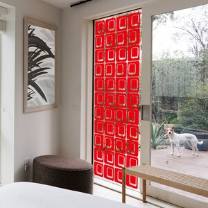 May include: A red geometric pattern window film with a repeating square design. The film is applied to a glass door leading to a backyard.