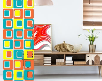 May include: A room divider made of wood with a geometric pattern of orange, yellow, and teal squares. The divider is in front of a white wall with a light fixture hanging from the ceiling. There is a wooden shelf with books and a vase on it.