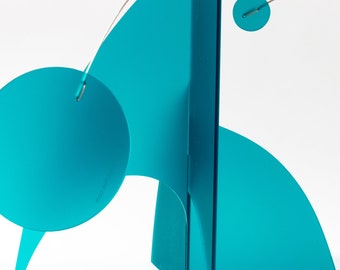 May include: A teal kinetic sculpture featuring flat, geometric shapes including circles and curved panels suspended by thin metal wires. The structure is composed of matte teal components connected by silver-toned metal rings and thin, curved metal rods.