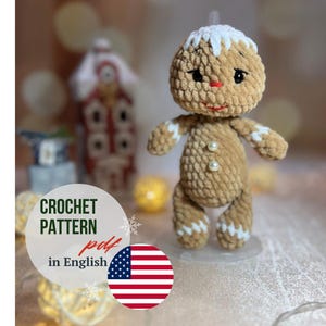 May include: Crochet pattern for a gingerbread man amigurumi toy. The pattern is in English and is available as a PDF download. The image shows a finished gingerbread man toy with white icing details and pearl buttons.