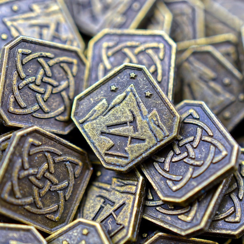 May include: A collection of bronze-colored, octagonal game tokens. Each token features a mountain and anvil design or Celtic knot patterns. The tokens have a weathered, antique appearance, suggesting use in fantasy or historical games.