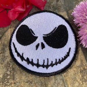 May include: White and black embroidered patch of Jack Skellington's face from the Nightmare Before Christmas film.