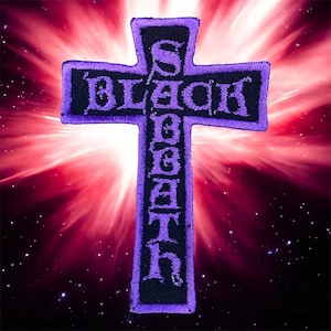 May include: Embroidered patch in the shape of a cross with the words "BLACK SABBATH" in purple lettering. The cross is outlined in purple and set against a black background. The background is a burst of red and white light.