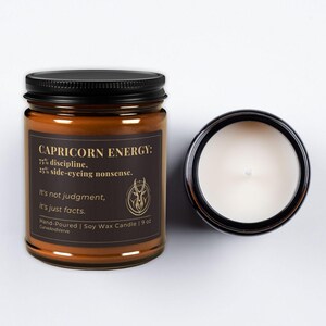 Capricorn Energy Candle with the lid off, showing the creamy soy wax and the sophisticated gold and black label design.
