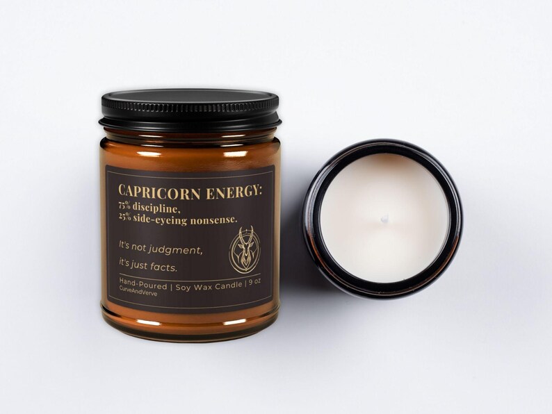 Capricorn Energy Candle with the lid off, showing the creamy soy wax and the sophisticated gold and black label design.