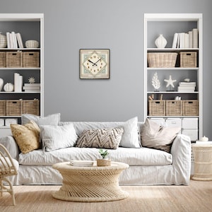 May include: A white couch with pillows and a woven coffee table in a living room with white shelves and baskets. A clock with a diamond shape and a cream background is on the wall.