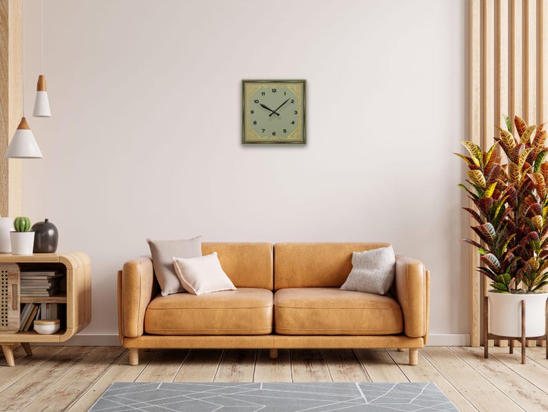 Art Deco wall clock styled above a mustard yellow couch with neutral décor and natural lighting.