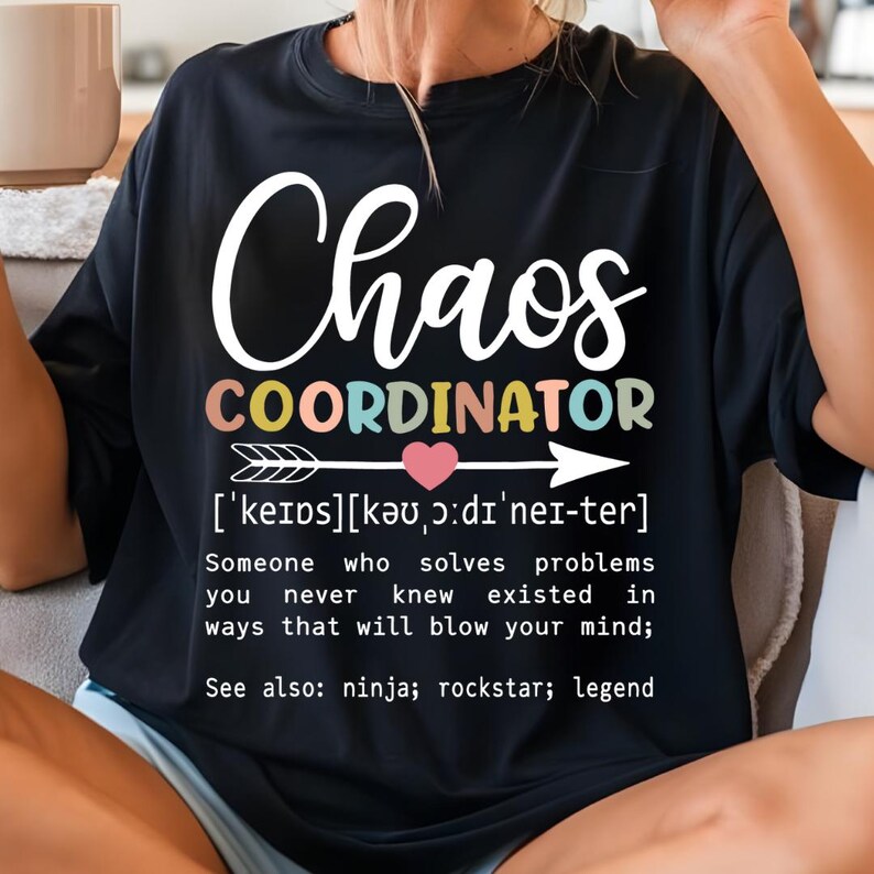 Może przedstawiać: Czarny T-shirt z białym tekstem, kt&oacute;ry brzmi "Chaos Coordinator" z definicją poniżej. Definicja brzmi: "['keips][kə ɔ:dı'nei-ter] Ktoś, kto rozwiązuje problemy, o kt&oacute;rych nigdy nie wiedziałeś, że istnieją, w spos&oacute;b, kt&oacute;ry rozsadzi ci m&oacute;zg; Zobacz także: ninja; rockstar; legenda"