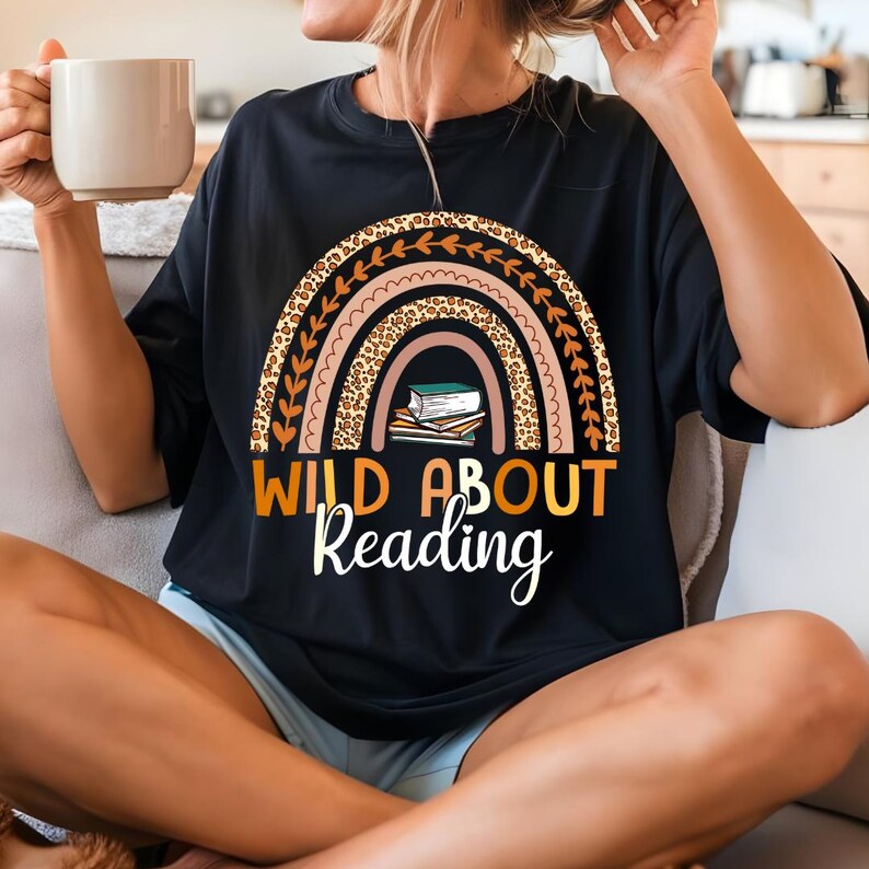 May include: Black t-shirt with a rainbow design featuring a leopard print and stacked books. The text "Wild About Reading" is printed below the rainbow.