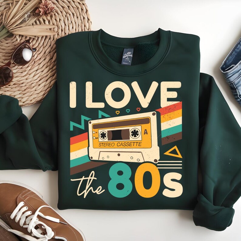 May include: A dark green sweatshirt with a retro-style graphic of a cassette tape and the text "I LOVE the 80s".