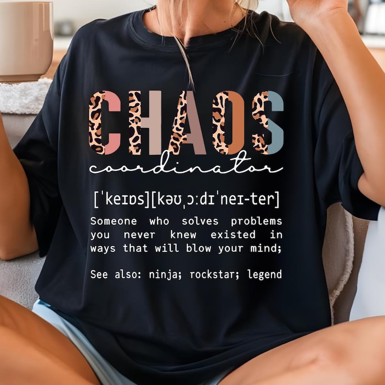 Może przedstawiać: Czarny T-shirt z napisem "CHAOS coordinator" w r&oacute;żowym, brązowym i niebieskim wzorze lamparta. Tekst "['keips][kǝu,ɔ:dı'nei-ter]" znajduje się pod tytułem. Tekst "Someone who solves problems you never knew existed in ways that will blow your mind; See also: ninja; rockstar; legend" znajduje się pod definicją.