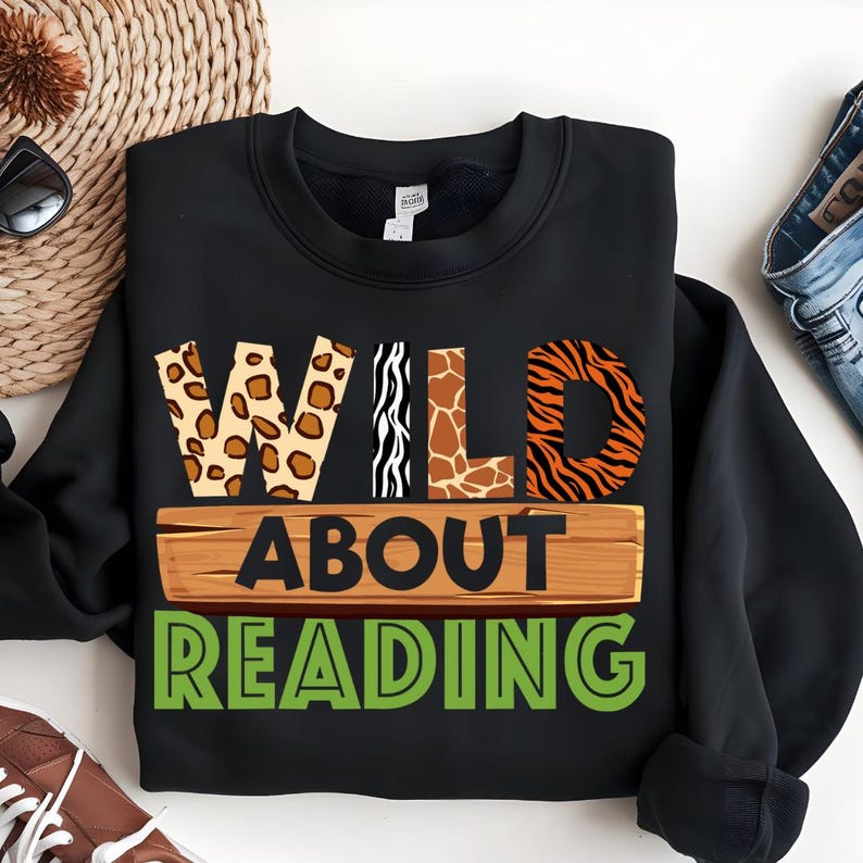May include: Black sweatshirt with the text "WILD ABOUT READING" in green letters. The word "WILD" is made up of animal print letters: leopard, zebra, giraffe, and tiger.