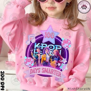 May include: Pink sweatshirt with a graphic featuring three animated figures, the text "KPOP DESIGN", and the words "100 DAYS SMARTER". The design includes a star, musical notes, and disco balls.