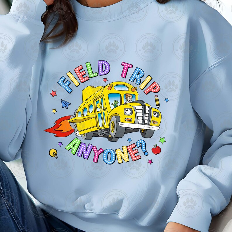 May include: Light blue sweatshirt featuring a yellow school bus graphic and the text "Field Trip Anyone?" in rainbow letters. The bus has a driver and a child passenger.