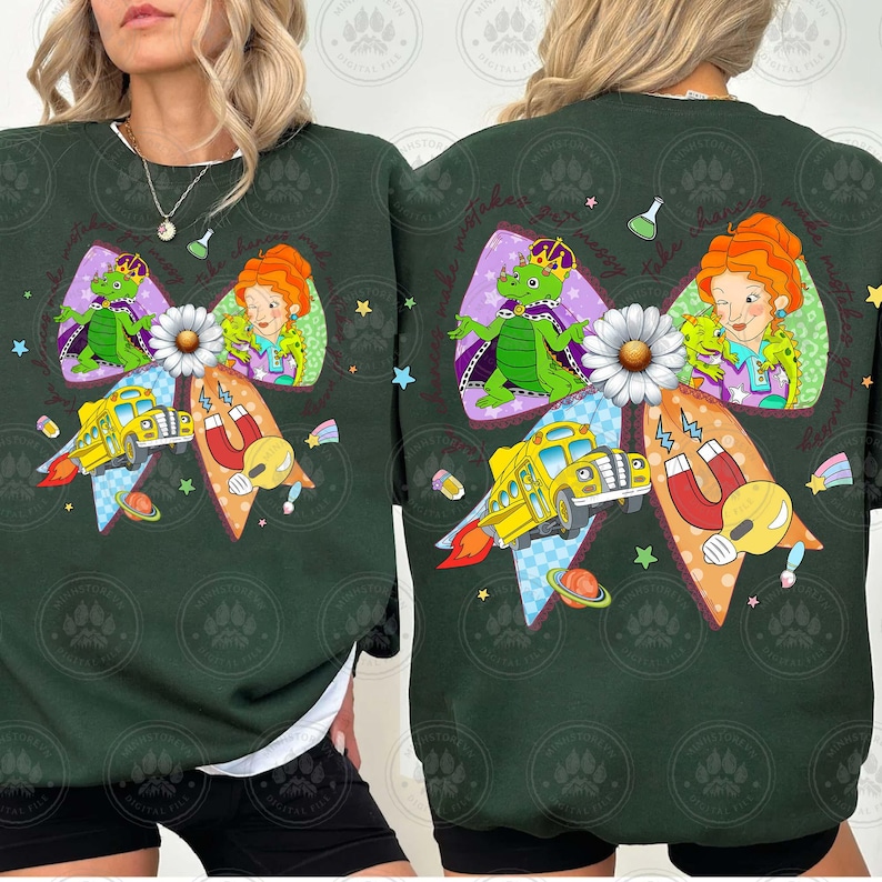 May include: Dark green sweatshirt featuring a colorful graphic. The design includes a bow with a daisy, a yellow school bus with flames, a dragon, and a woman with red hair. The sweatshirt has a white lining.