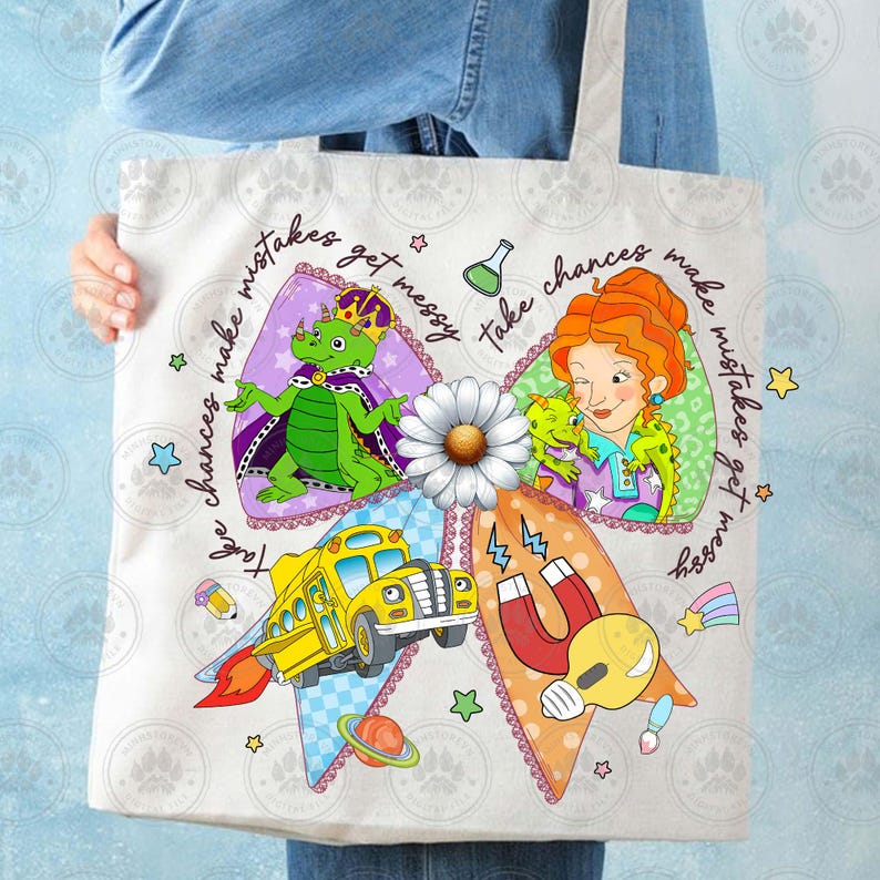 May include: A white tote bag featuring a colorful cartoon design. The design includes a yellow school bus with flames, a green dragon wearing a crown, and a woman with red hair. Text reads "Take chances make mistakes get messy."