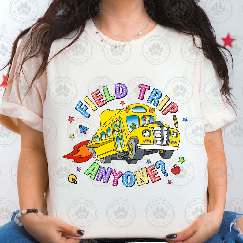 May include: White t-shirt featuring a colourful graphic of a yellow school bus with the text "Field Trip Anyone?"
