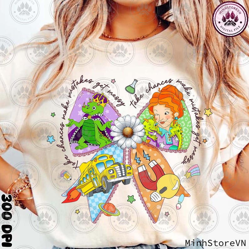 May include: Cream-colored t-shirt featuring a colorful graphic design. The design includes a bow shape with illustrations of a school bus, a dragon, a teacher, and a magnet. Text on the shirt reads "Take chances, make mistakes, get messy."